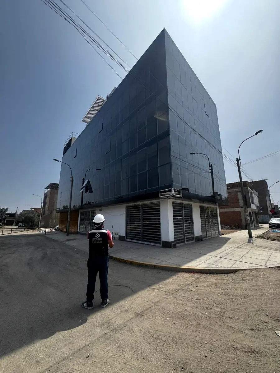 Edificio de fachada oscura con supervisor en la vereda