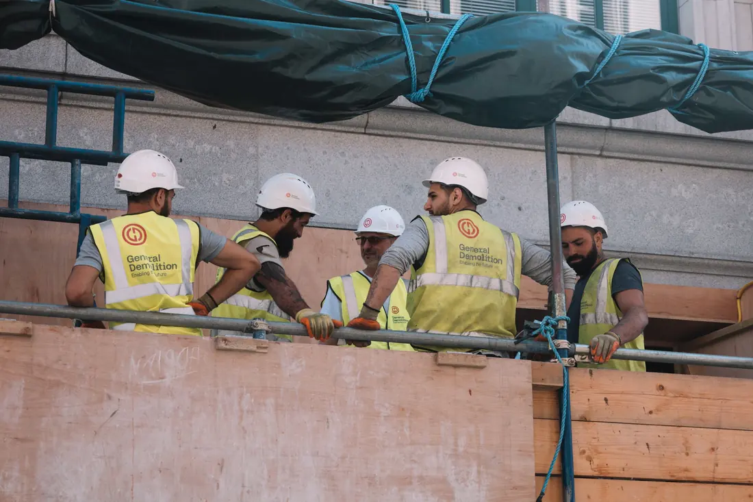Cuadrilla de obreros con casco coordinando trabajos en altura